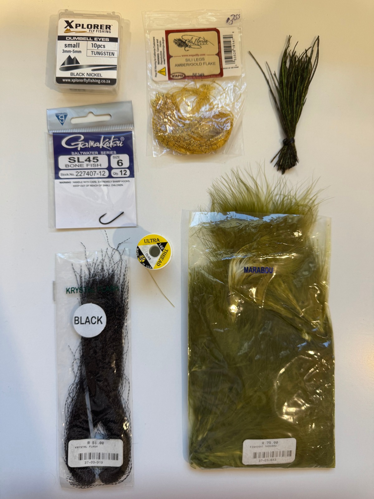Fly tying materials laid out for best permit flies, including marabou, hooks, rubber legs, and UV thread for fly fishing in Grand Cayman, Cayman Islands